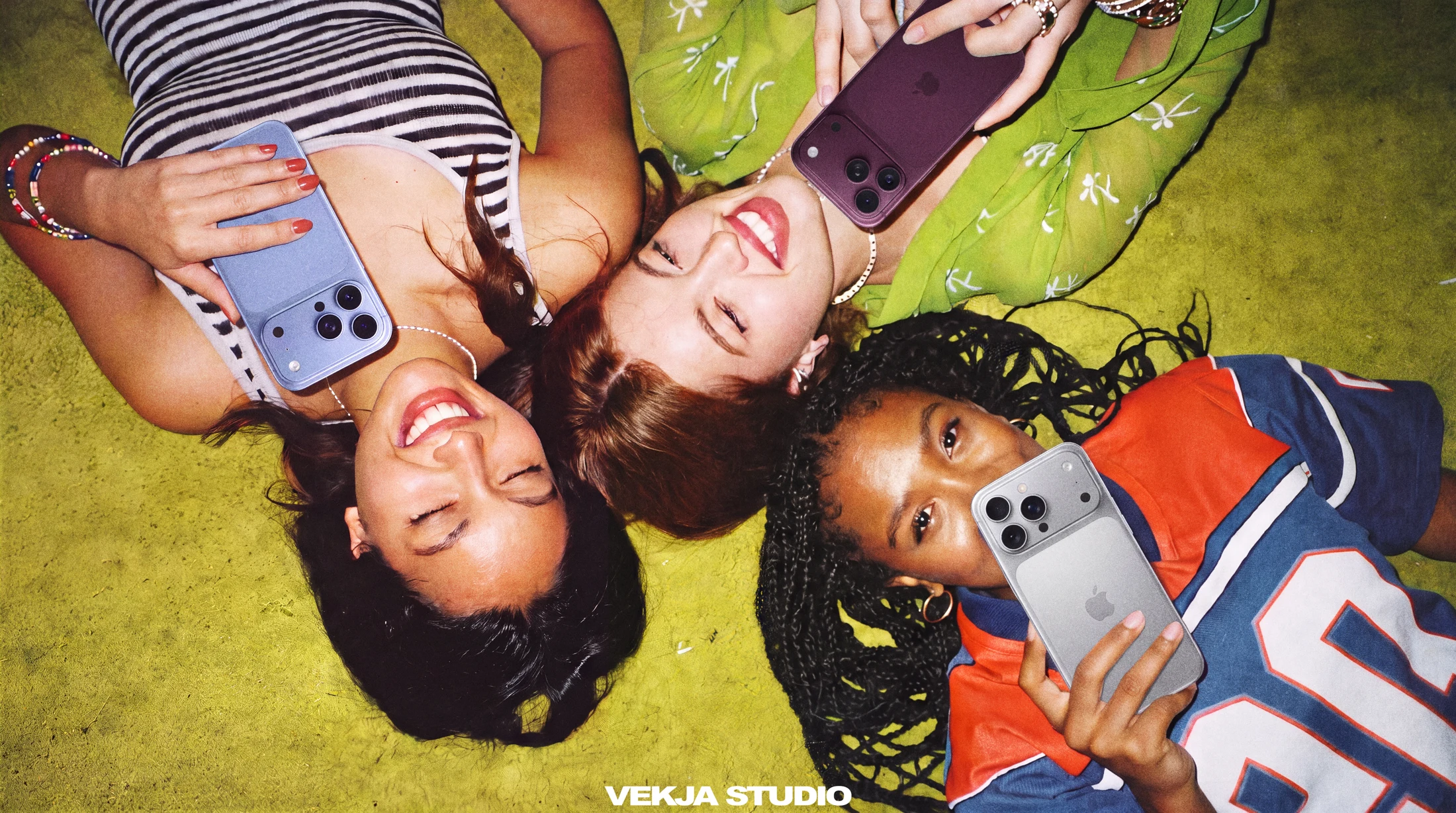 Three friends with phones on a green carpet