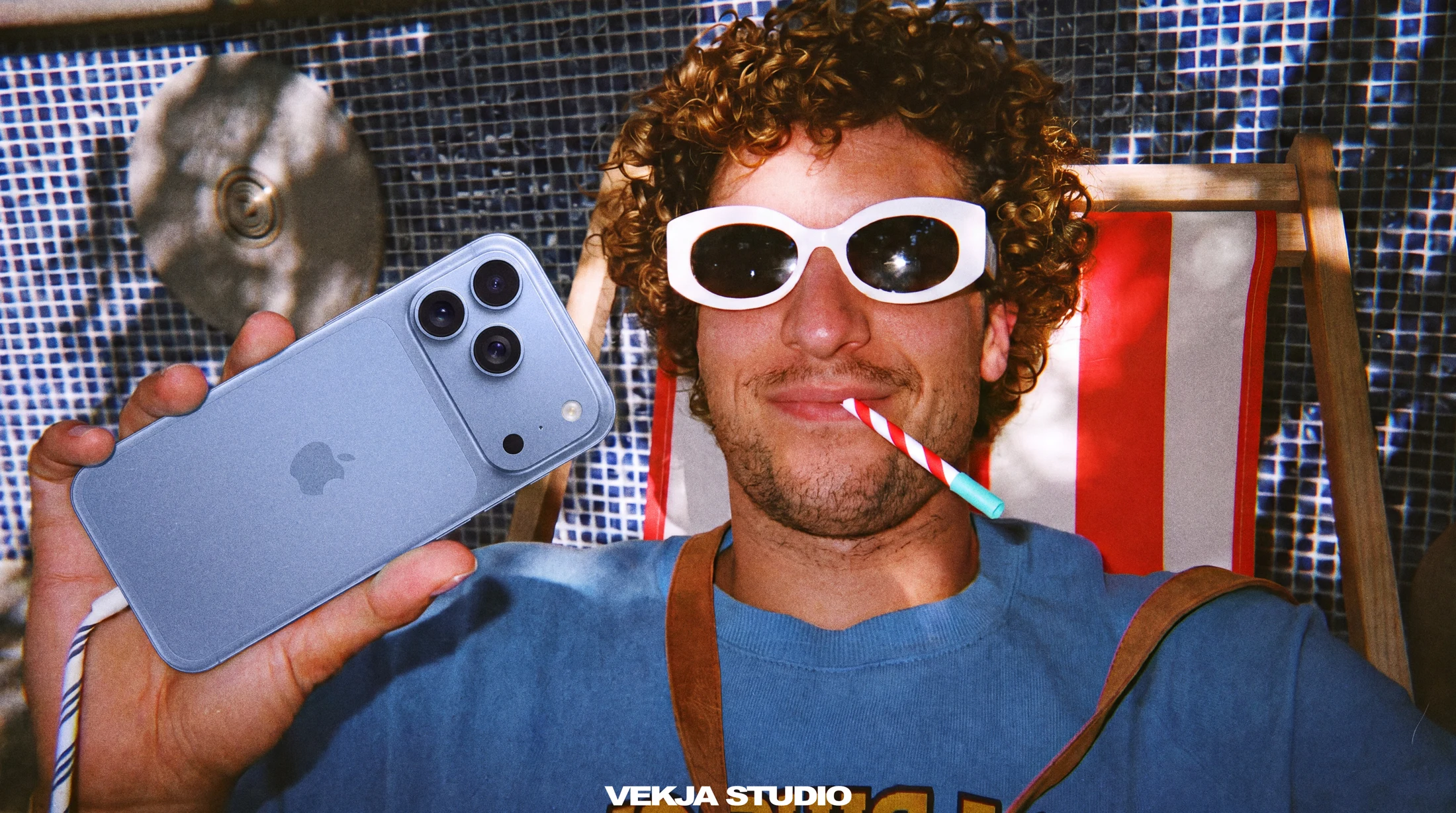 Man with white sunglasses holding a blue phone
