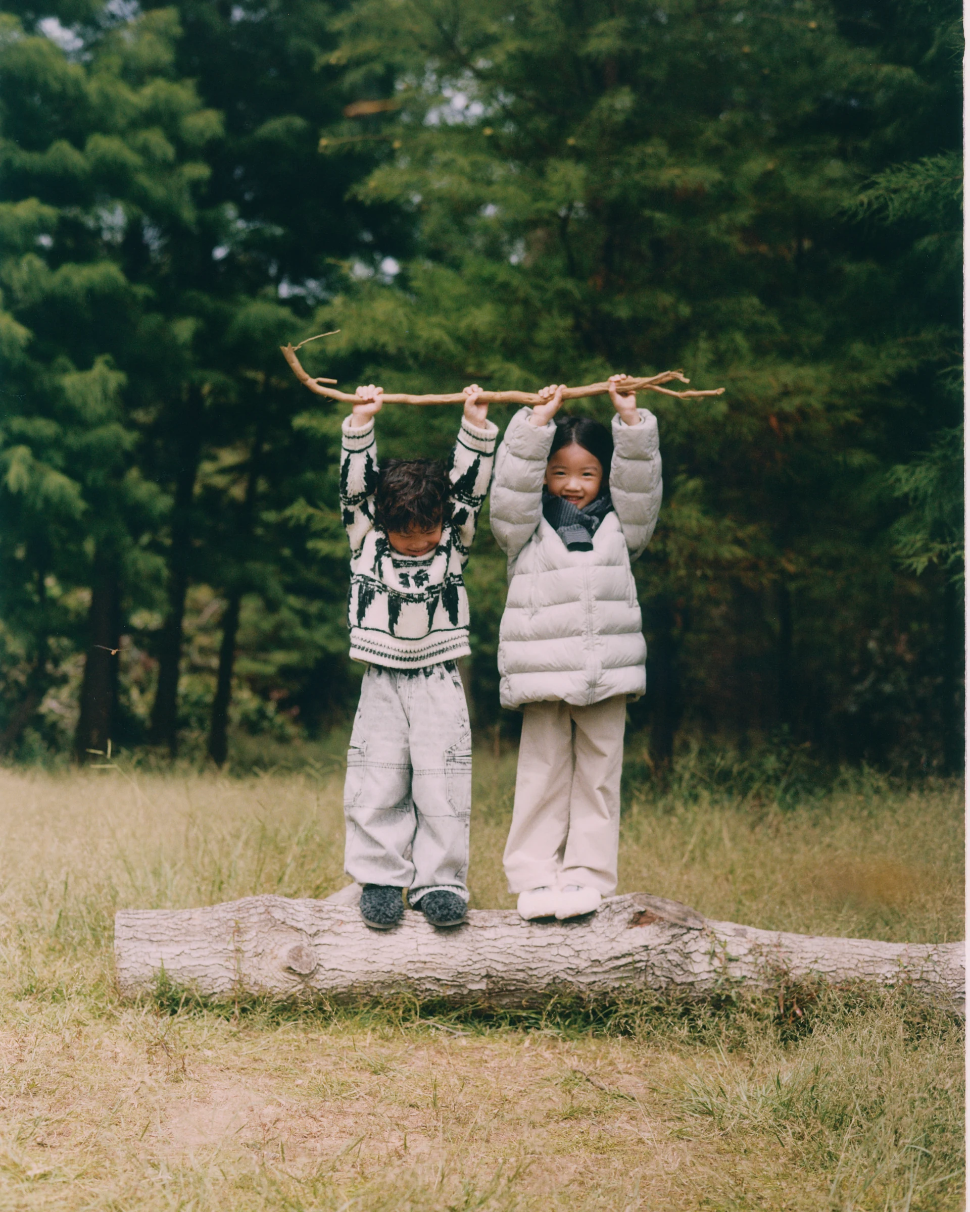 Two children lifting a branch together in jnby by JNBY outerwear