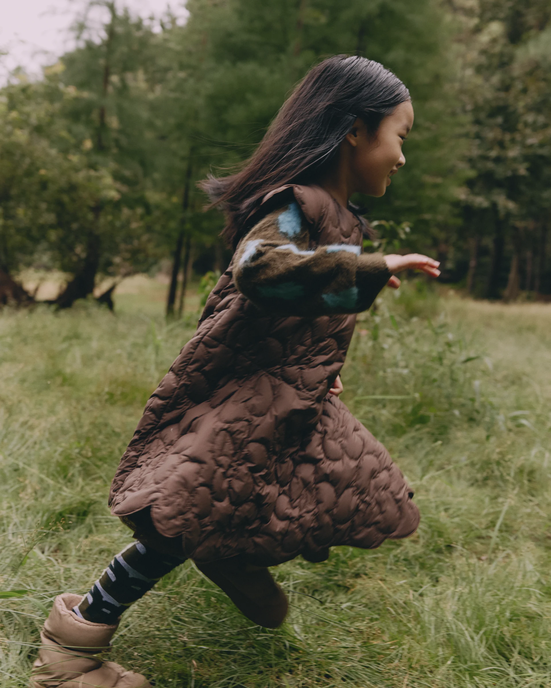Girl running through woodland in a brown jnby by JNBY quilted vest