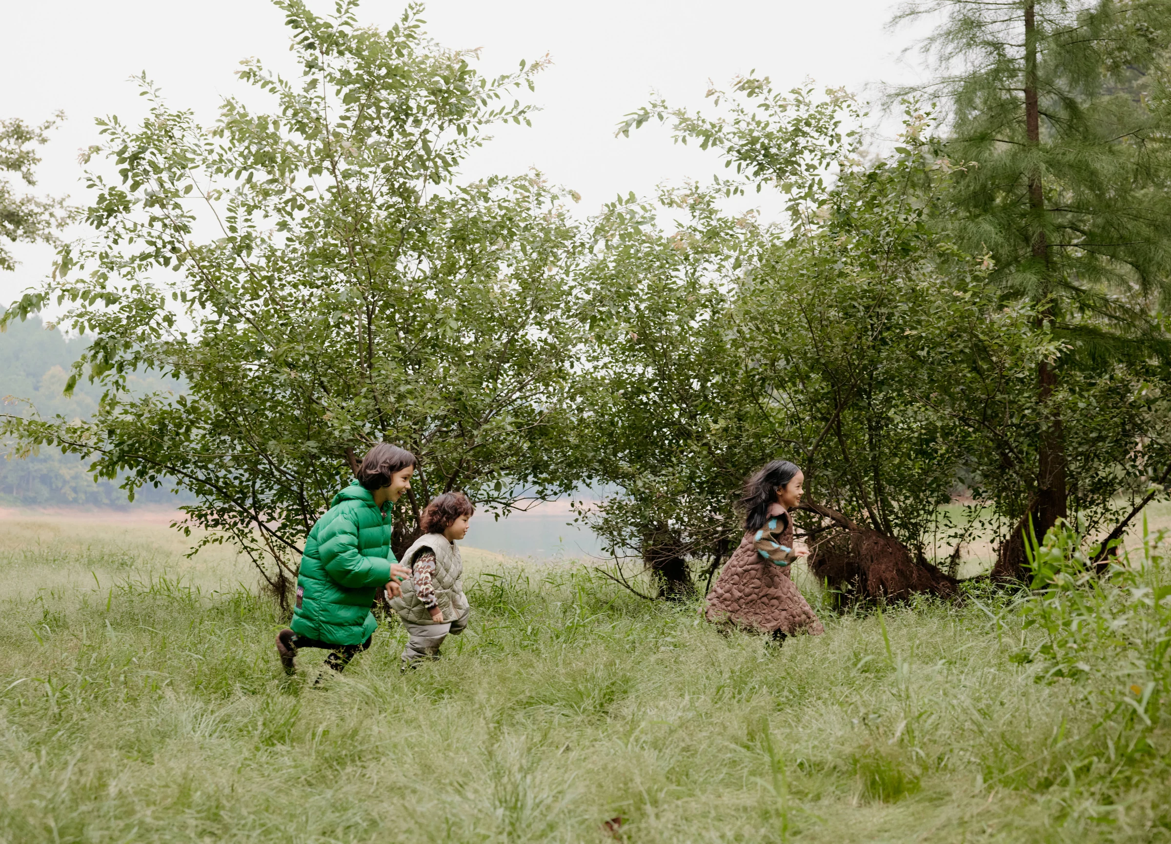 Children playing together among trees in jnby by JNBY outerwear