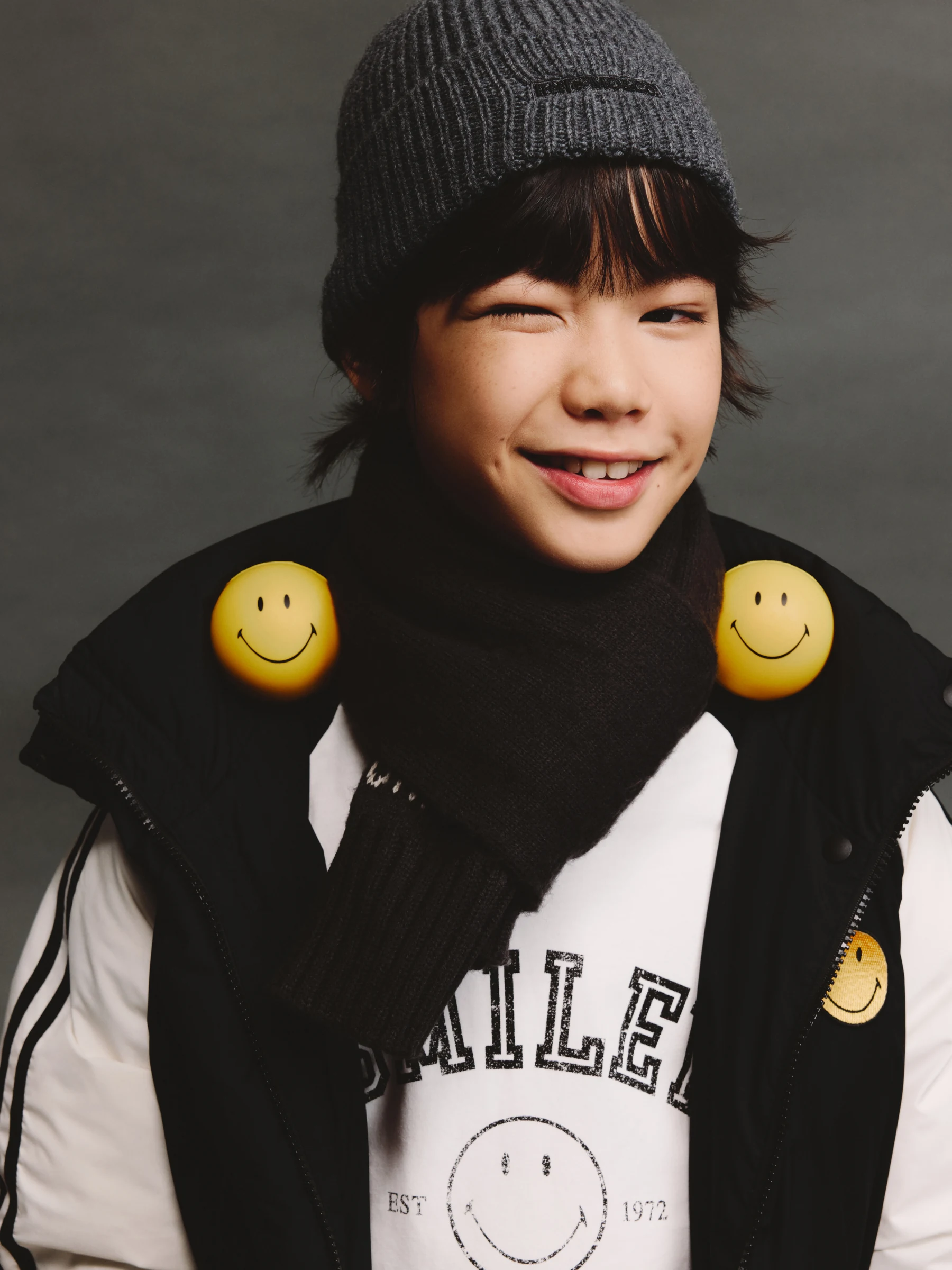 Smiling child in a knit hat with yellow smiley details