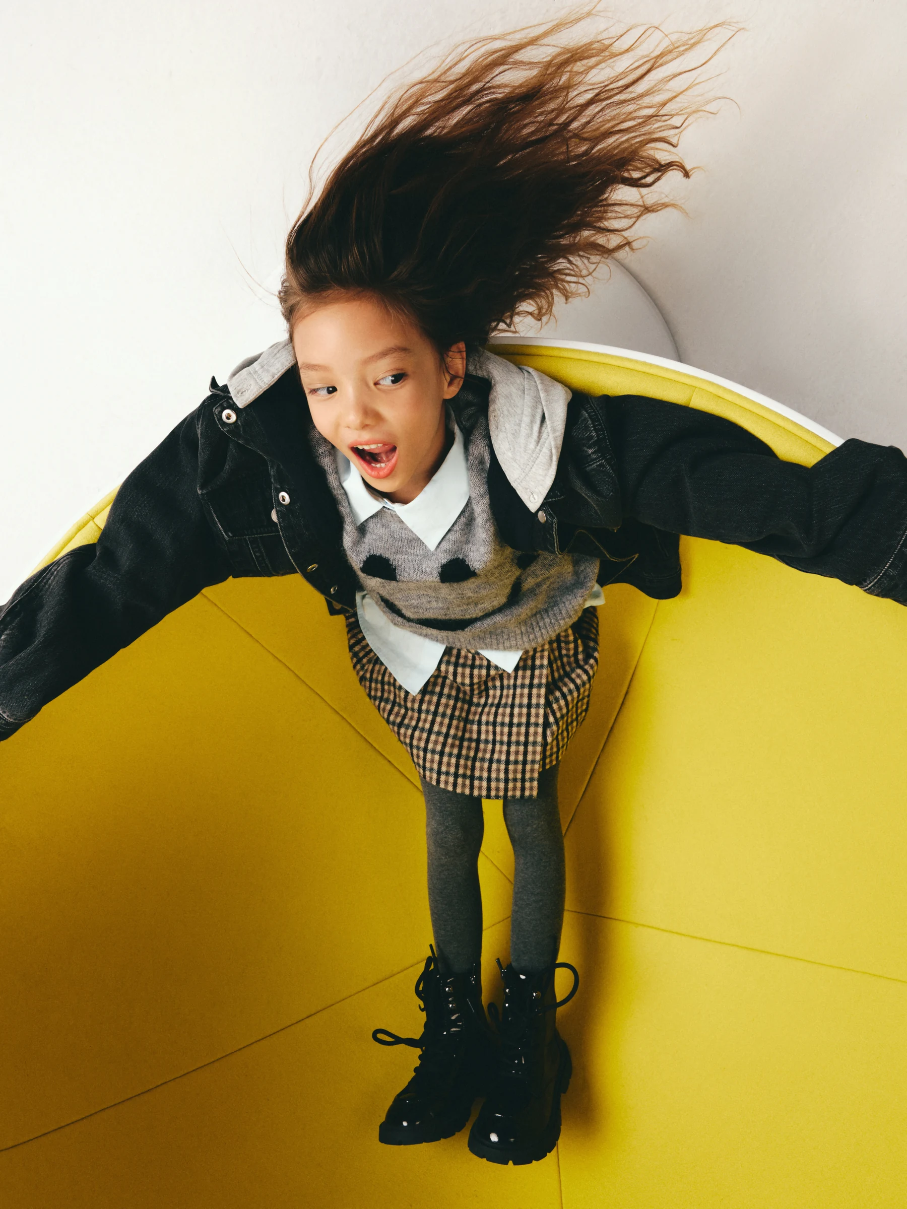 Child jumping against a sculptural yellow backdrop