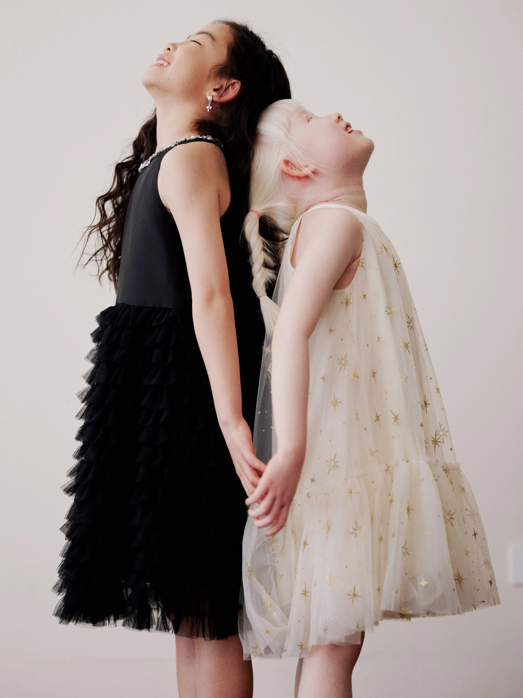 Two girls holding hands in black and cream dresses