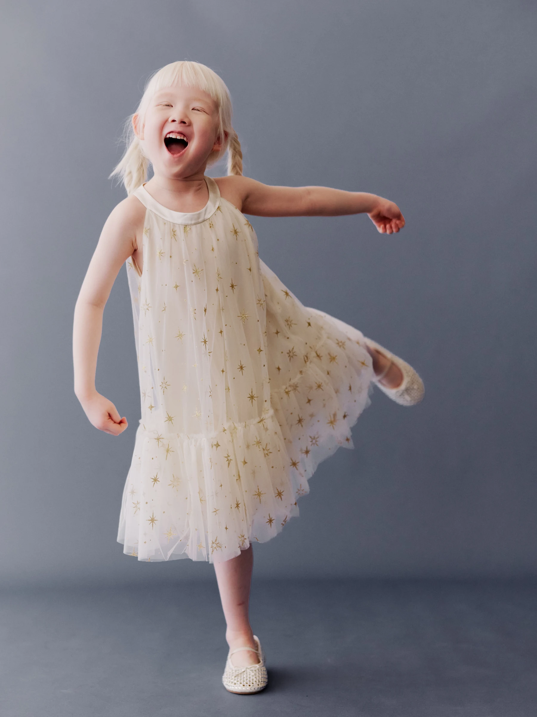 Child dancing in a cream star-pattern dress