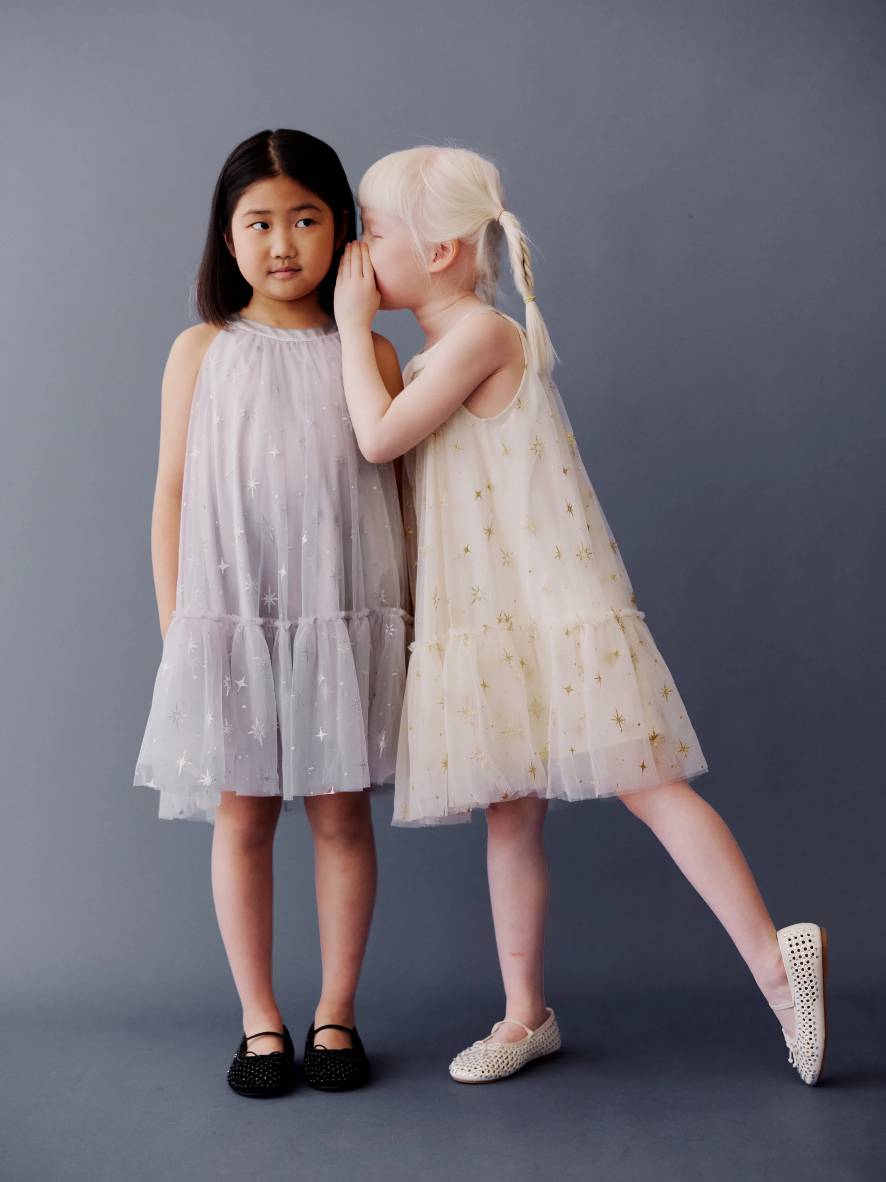 Two girls sharing a whisper in lilac and cream dresses
