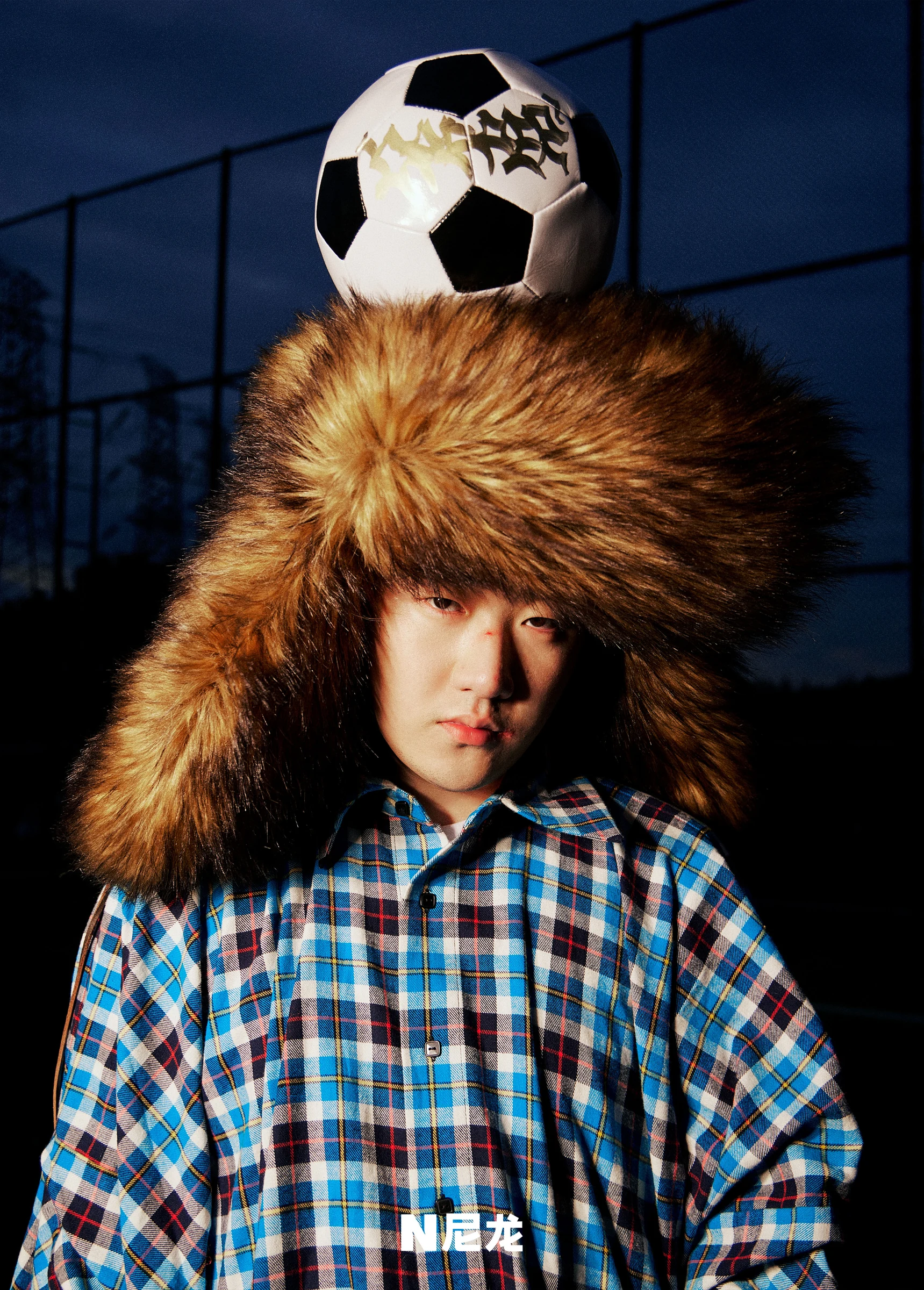 Capper in a fur hat with a football above his head for NYLON
