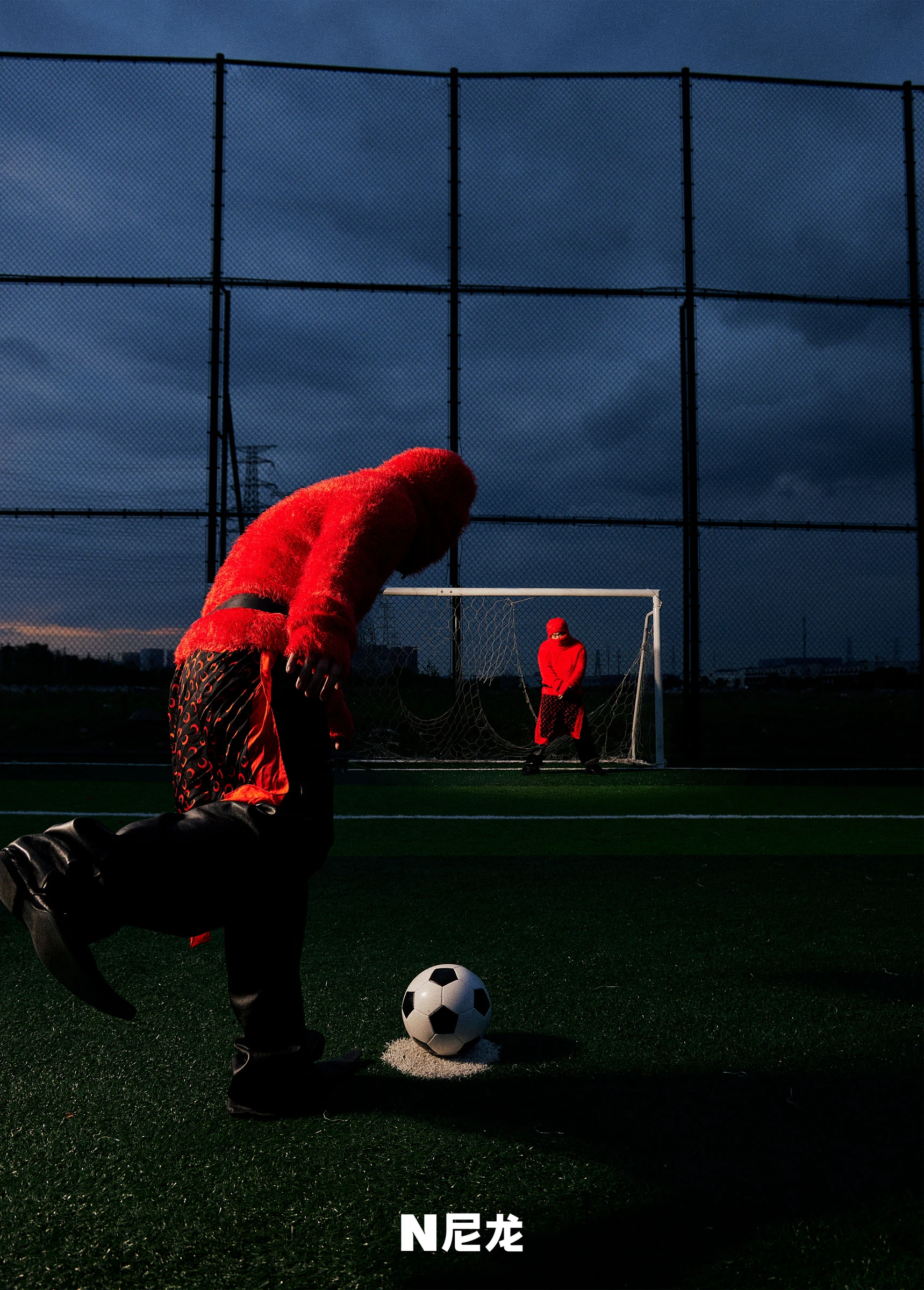 Capper in a red outfit on a football pitch for NYLON