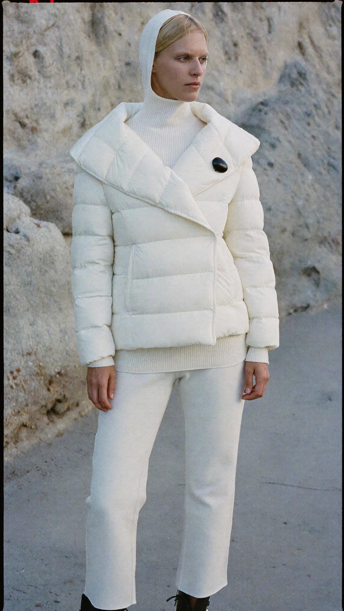 Cream quilted jacket against pale rock
