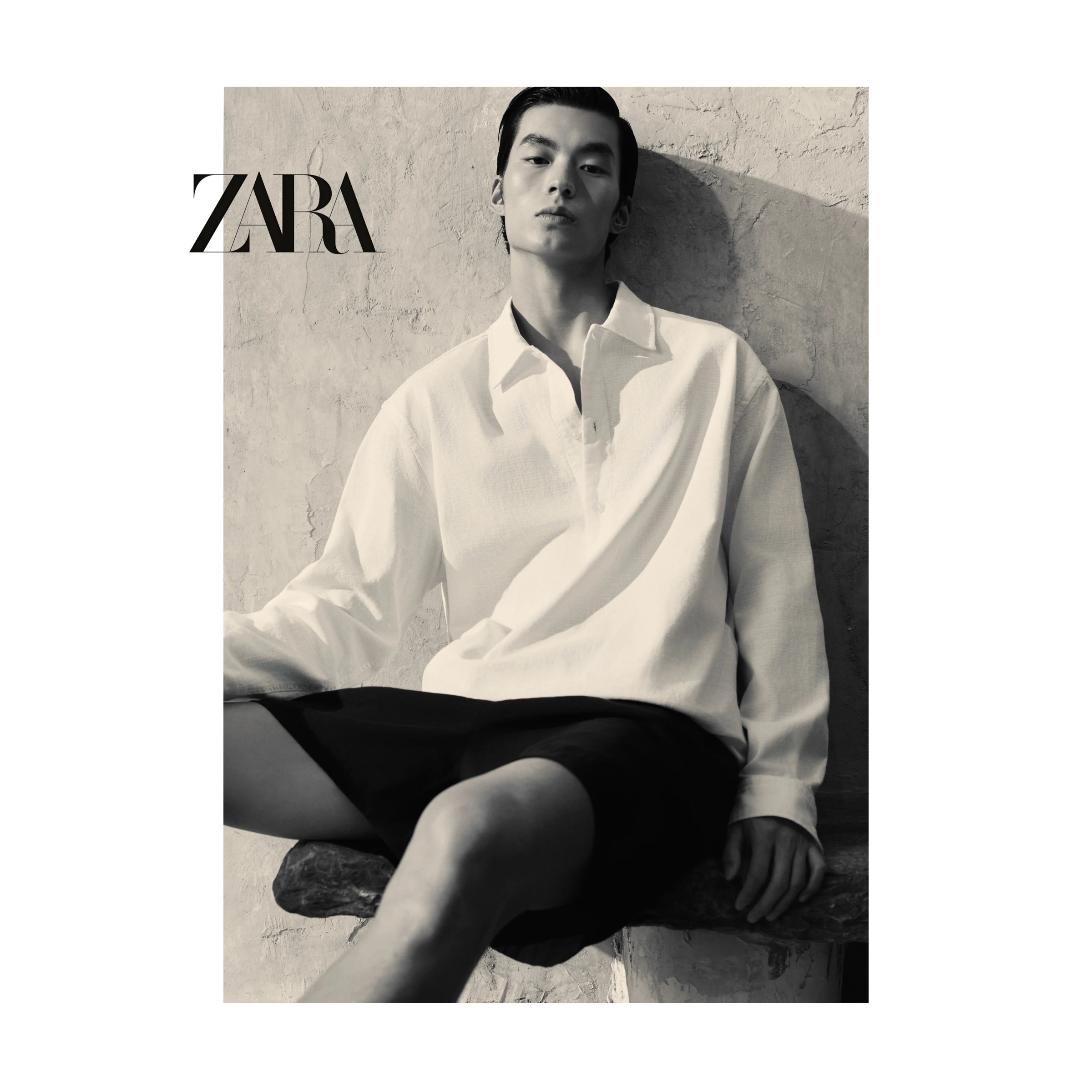Black-and-white ZARA seated portrait in a white shirt